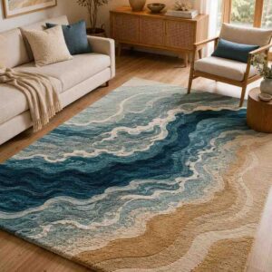 Coastal ocean wave area rug featuring a textured abstract beach design in deep blue, teal, and sandy beige in a bright, modern living room.