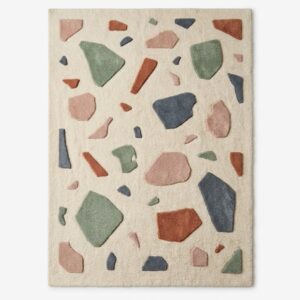 Terrazzo pattern area rug featuring scattered geometric stone shapes in pastel pink, sage green, slate blue, and terracotta on a cream background.